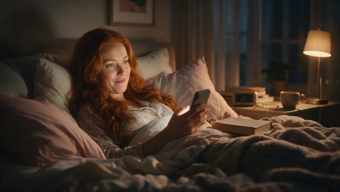 Woman looking startled at the time on her phone in bed at night